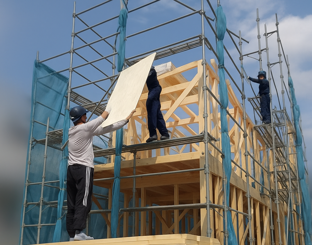 木造住宅建設現場にて材木を荷揚げしている様子